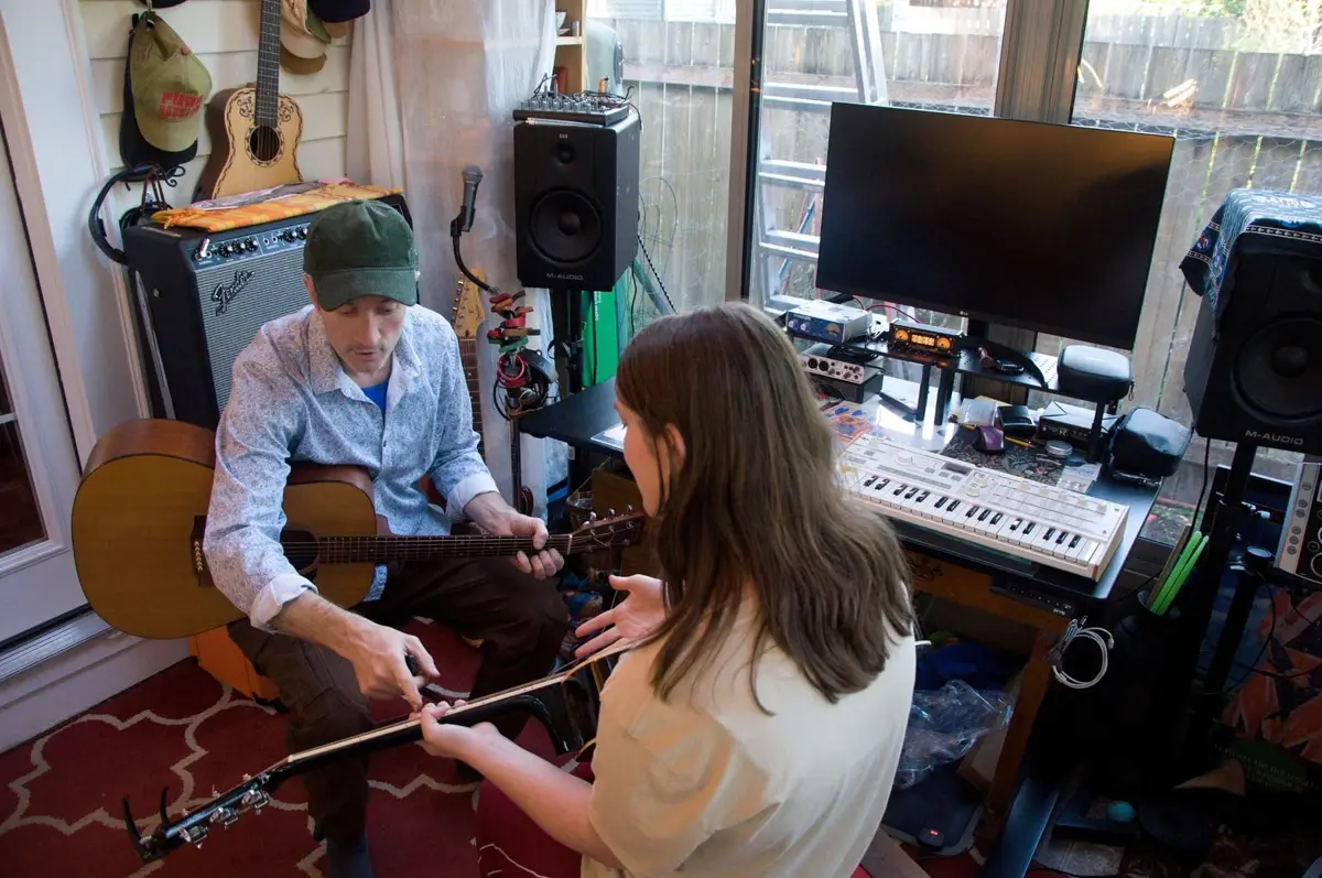 A student learning acoustic guitar during a lesson in the West Seattle studio